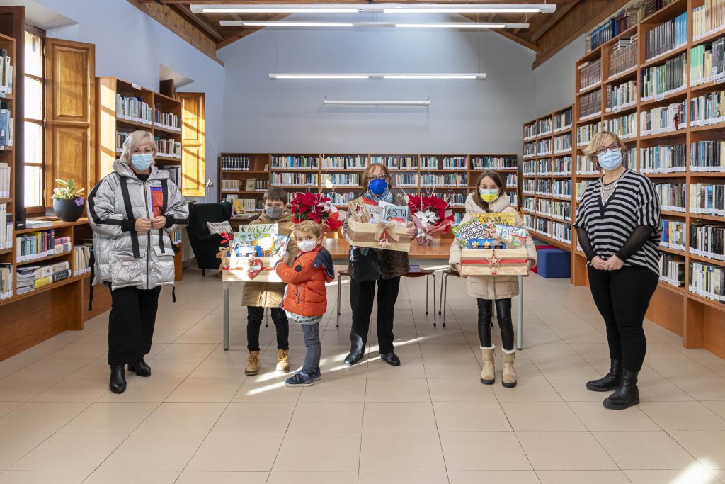 La alcaldesa y la responsable de la biblioteca con los Ganadores de las cestas de la iniciativa “Leer tiene premio”