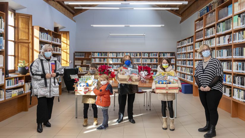 La alcaldesa y la responsable de la biblioteca con los Ganadores de las cestas de la iniciativa “Leer tiene premio”