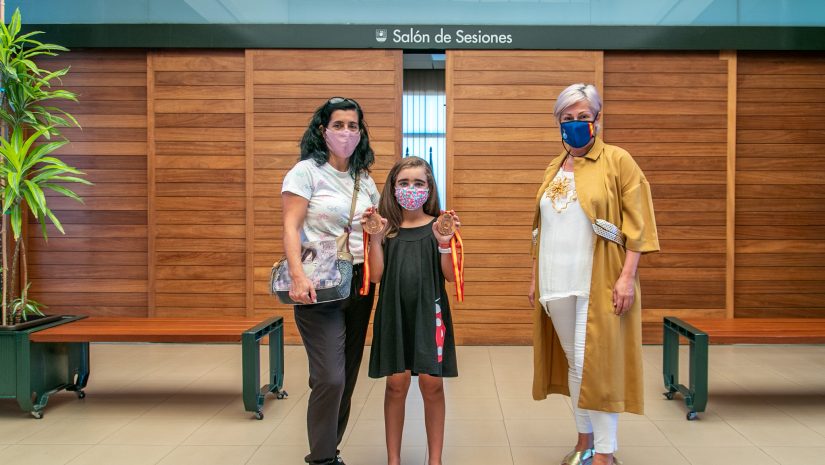 Rocío García Saiz, acompañada por su madre, muestra sus medallas a la alcaldesa de Polanco