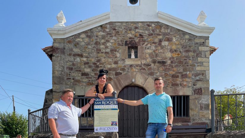 El concejal de Festejos, Fernando Sañudo (primero por la izquierda), sostiene el cartel de la fiestas de Posadillo junto a la ermita del pueblo, acompañado de los concejales Isabel Herrera y David Esteban