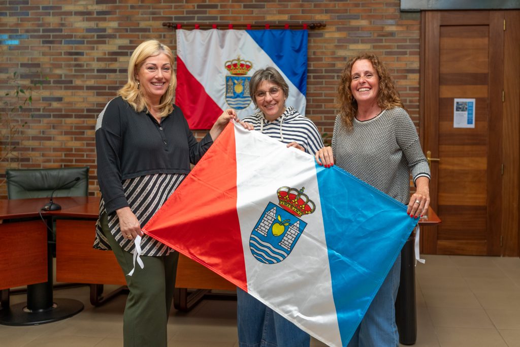 La alcaldesa, Rosa Díaz, y la concejal de Cultura, Alicia Martínez Bustillo, entregan la bandera de Polanco que la montañera Raquel García plantará en lo alto del glaciar tropical Quelccaya