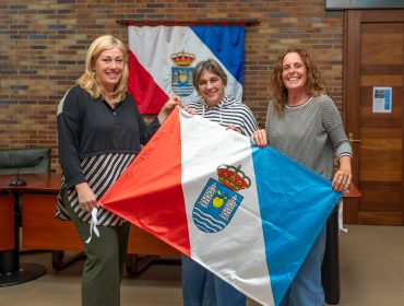 La alcaldesa, Rosa Díaz, y la concejal de Cultura, Alicia Martínez Bustillo, entregan la bandera de Polanco que la montañera Raquel García plantará en lo alto del glaciar tropical Quelccaya